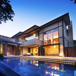 夕暮れ時、ライトアップされたプールのある建物外観