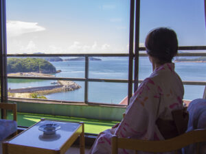Personne en yukata admirant la vue sur l’océan depuis la chambre