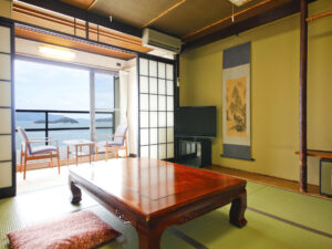 Chambre en tatami avec table basse et chaises face à l’océan