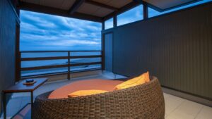 Fauteuil lounge en osier sur le balcon face à la vue sur l’océan