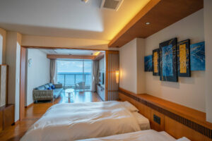 Camera da letto con letti e zona salotto accanto a una finestra con vista sull’oceano