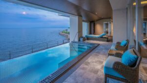Piscina a sfioro coperta con vista sull’oceano e lettini