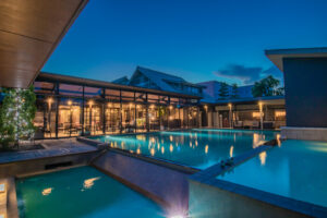 Area piscina all'aperto di notte con edificio illuminato