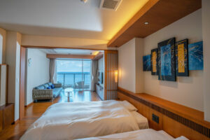 Letti singoli in una camera con area salotto e balcone.