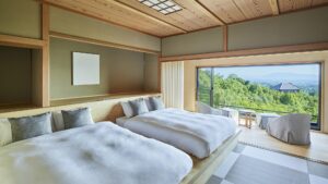 Twin beds beside window with seating and mountain view