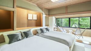 Two beds beside a window seating area.