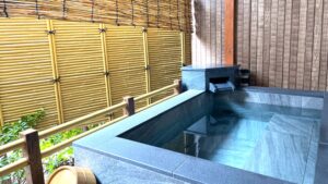 Baño rectangular privado con mampara de bambú y paredes de madera