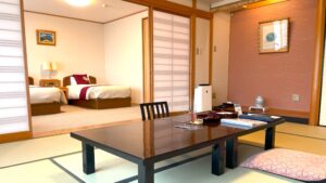 Habitación de tatami con mesa baja y camas contiguas