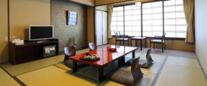 Habitación de tatami con mesa baja, sillas de suelo y asientos junto a la ventana