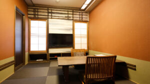 Tatami room with low table, chairs, and television