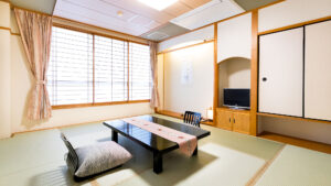 Habitación de tatami con mesa baja, cojines de suelo y televisión