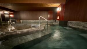 带瓷砖浴池和扶手的室内公共浴场