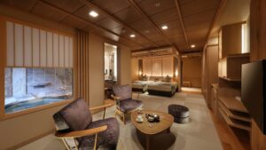 Habitación con sillas, mesa, camas y ventana al baño