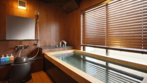 Baño privado de madera junto a una ventana con persianas