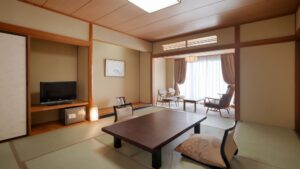 Habitación de tatami con mesa baja, sillas y televisión