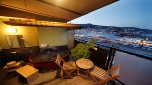 Baño al aire libre en el balcón con sillas y vista al puerto