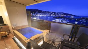 Baño al aire libre privado junto al balcón con vistas al puerto nocturno