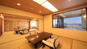 Habitación de tatami con mesas bajas y sillas junto a la ventana