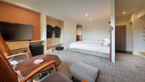 Guest room with bed, chairs, and wall-mounted TV