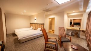 Twin beds in a guest room with chairs and desk