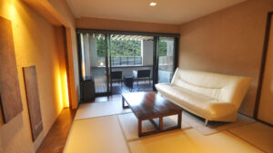 ソファ、テーブル、バルコニーチェアのある畳の客室