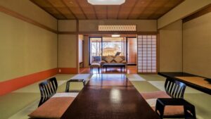 Camera in tatami con tavolo basso e area salotto accanto alla finestra