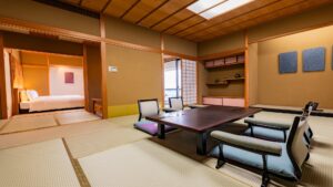 Camera in tatami con tavolo basso, sedie da pavimento e alcova con letto