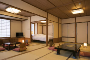 Habitación de tatami con mesas bajas y camas contiguas