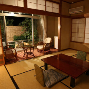 Habitación de tatami con mesa baja y sillas junto a la ventana