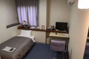 Single bed beside desk and chair in compact room