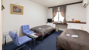 Twin beds with chairs and window in guest room