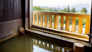 Baño privado junto a una ventana abierta con vistas a la montaña