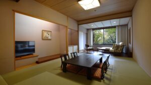 Camera con tatami, tavolo basso, sedie e posti a sedere vicino alla finestra