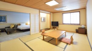 Camera in tatami con tavolino basso, cuscini e zona letto adiacente