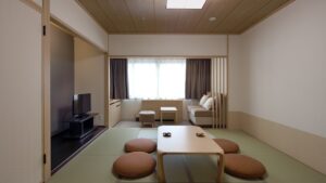 Camera in tatami con tavolo basso, cuscini da pavimento e divano