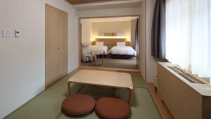 Zona salotto in tatami di fronte a una camera con due letti singoli