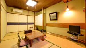 Habitación de tatami con mesa baja, sillas de suelo y TV