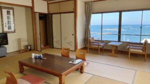 Camera in tatami con tavolo basso e sedie rivolte verso il mare
