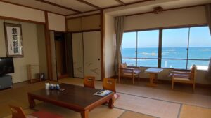 Camera in tatami con tavolo basso, sedie e finestra con vista sull’oceano