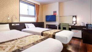 Letti singoli in una camera con scrivania e TV