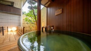 Baño privado redondo junto a una terraza de madera y un jardín