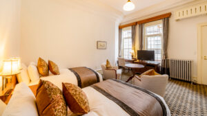 Camas individuales en una habitación con escritorio y sillas