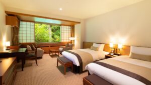 Dos camas individuales en una habitación con asientos junto a la ventana