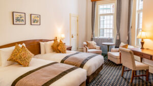 Habitación con dos camas individuales, sillas y escritorio