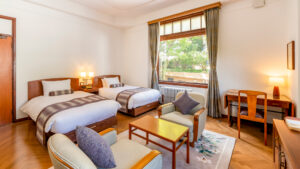 Habitación con dos camas individuales, zona de estar con sofá y escritorio