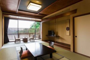 Camera in tatami con tavolo basso e sedie accanto al balcone