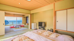 Futons in tatami room facing a balcony seating area