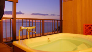 Open-air bath on balcony overlooking the sea at dusk