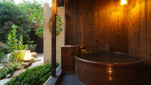 Private wooden bathtub beside a garden-facing window