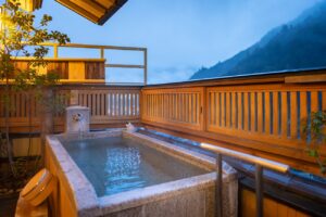 山の景色を望む木製バルコニーの専用露天風呂